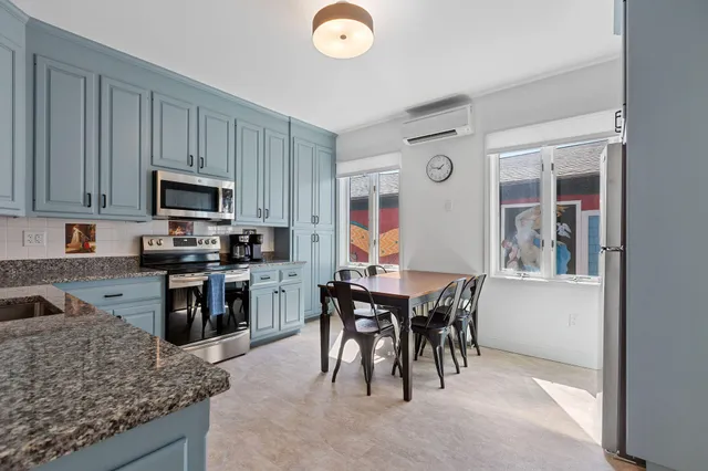 a kitchen with stainless steel appliances granite countertop a stove top oven a sink a dining table and chairs with wooden floor