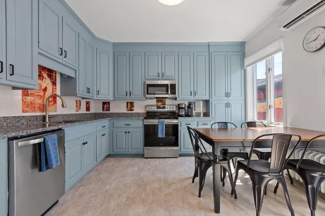 a kitchen with stainless steel appliances granite countertop a stove top oven a sink dishwasher and a refrigerator with wooden cabinets