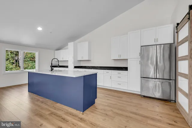 a kitchen with wooden floors white cabinets and stainless steel appliances