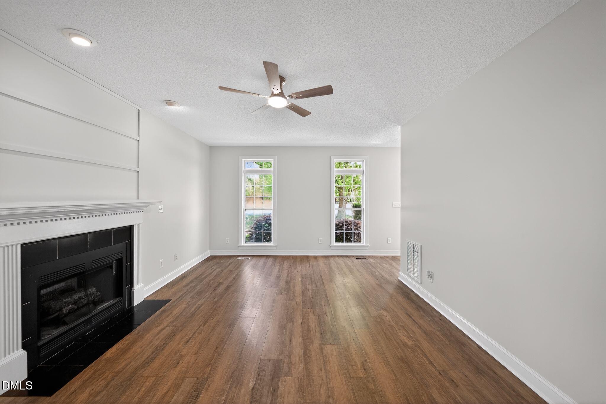 641 Commander Drive Wendell, NC 27591 - Photo 4 of 15 an empty room with wooden floor fireplace and windows