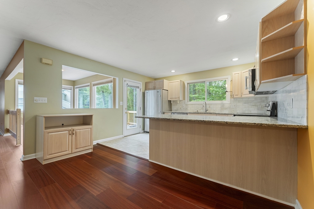 22 Arrowhead Circle, Unit 22 Ashland, MA 01721 - Photo 8 of 35 a kitchen with stainless steel appliances granite countertop a stove a sink and white cabinets with wooden floor next to windows
