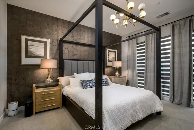 a bedroom with a bed a flat screen tv and a chandelier