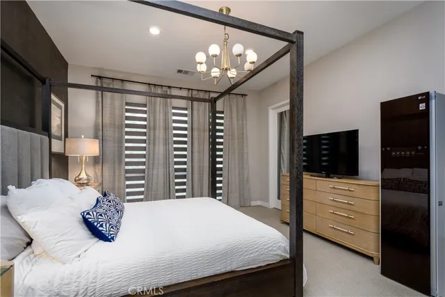 a bedroom with a large bed and a lamp on dresser