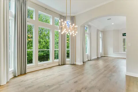 a view of a livingroom with a chandelier curtains and large windows