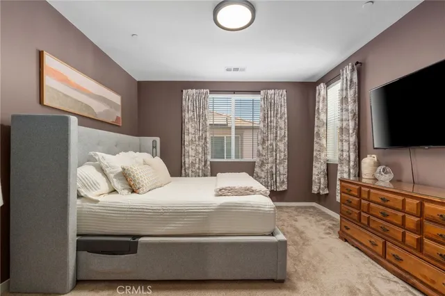 a bedroom with a bed and a flat tv screen on dresser