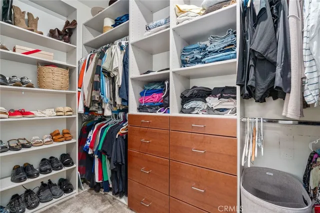 a view of walk in closet with clothes and shoes