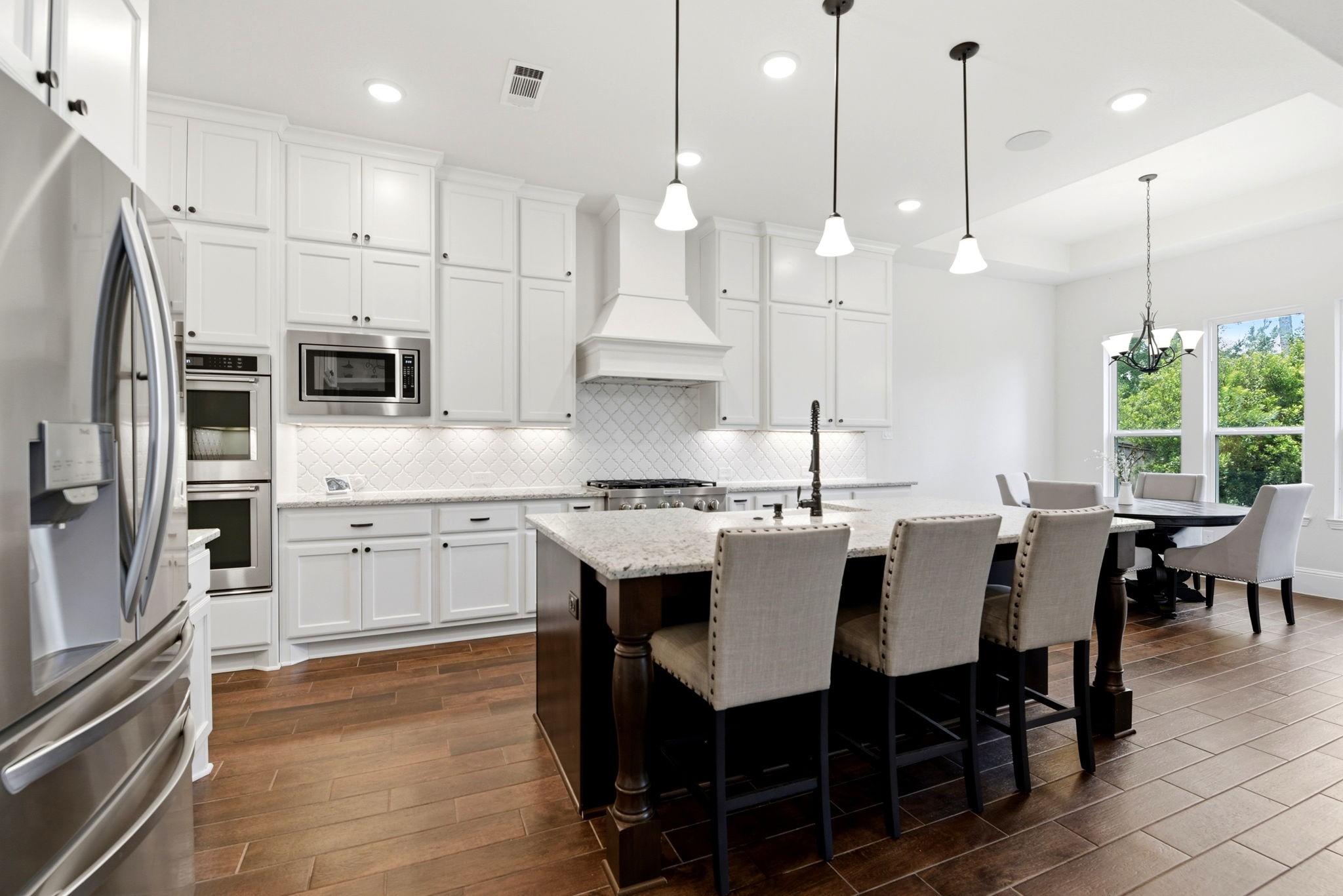 10062 South Goshawk Trail Conroe, TX 77385 - Photo 9 of 43 a kitchen with stainless steel appliances granite countertop a sink a stove a kitchen island with a dining table and chairs
