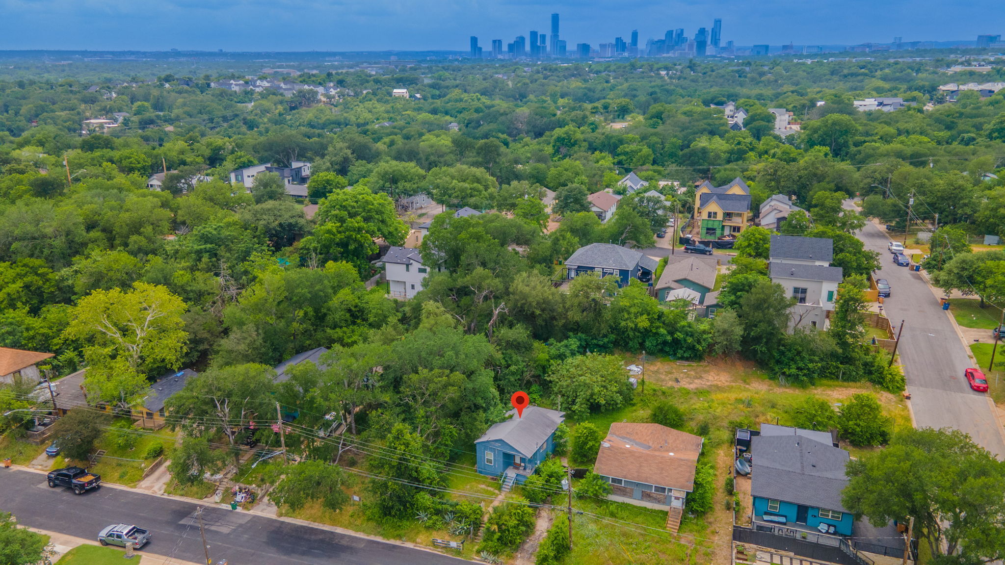 1408 Luna Street Austin, TX 78721 - Photo 1 of 5 An aerial perspective reveals a vibrant, tree-filled neighborhood with distant city views.
