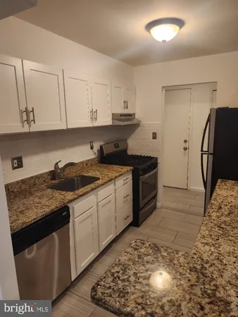 a kitchen with stainless steel appliances granite countertop a stove a sink and a refrigerator