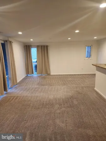 a view of an empty room with wooden floor and a kitchen