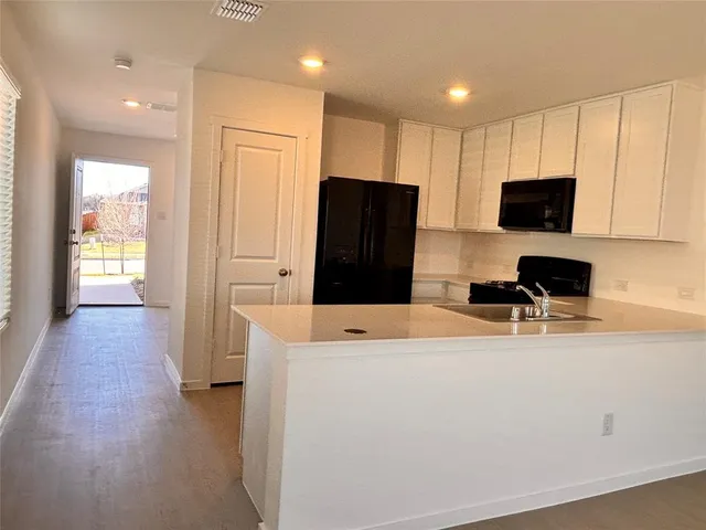 a kitchen with stainless steel appliances a refrigerator oven a microwave oven with white cabinets and wooden floor