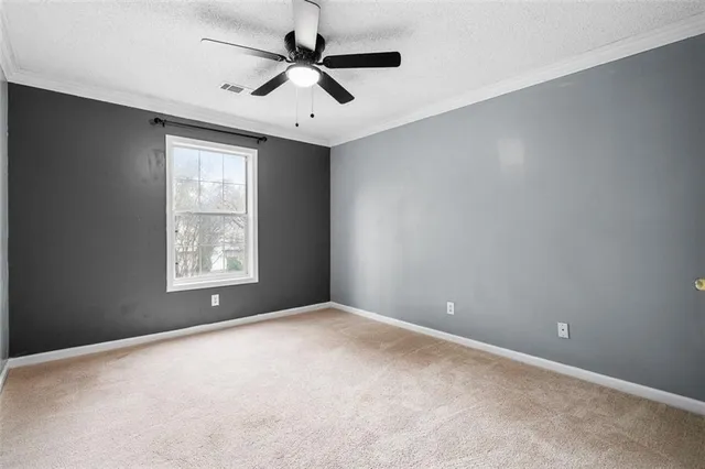 an empty room with a ceiling fan and windows