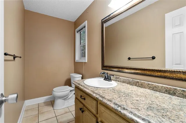 a bathroom with a granite countertop sink a toilet and mirror