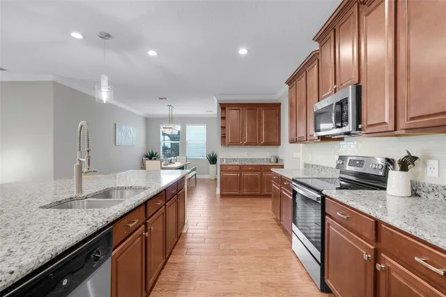 a dining room with stainless steel appliances kitchen island granite countertop a dining table chairs and a oven