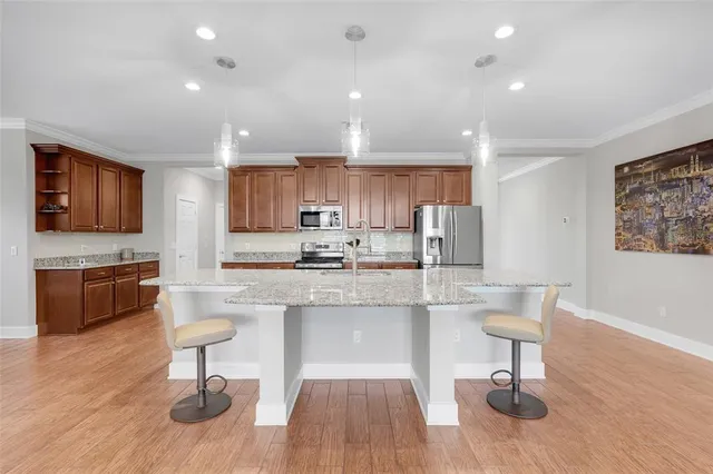 a kitchen with stainless steel appliances granite countertop a stove top oven a sink dishwasher a dining table and chairs with wooden floor