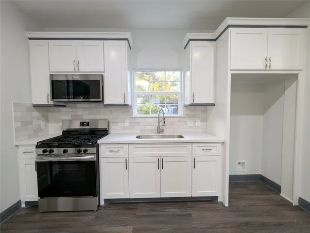 a kitchen with cabinets stainless steel appliances and wooden floor