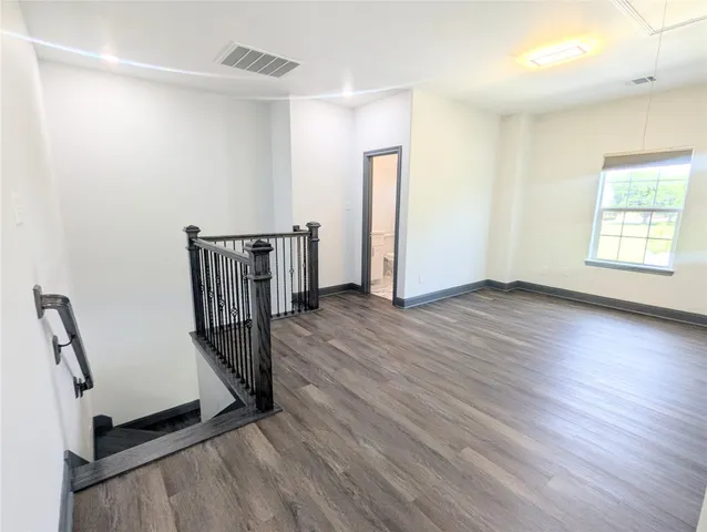a view of a hallway with wooden floor and stairs