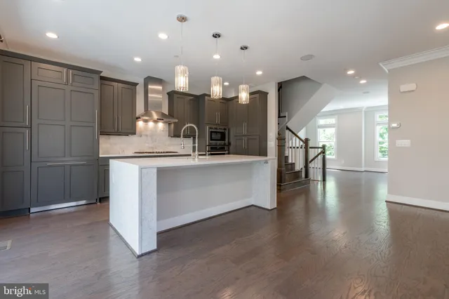 a large kitchen with stainless steel appliances a large counter top a stove and a refrigerator