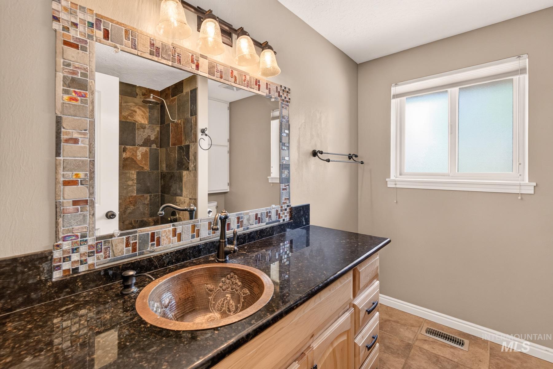 9622 Delaware Street Boise, ID 83709 - Photo 29 of 48 Bathroom featuring a copper vessel sink, dark stone countertop, and light wood cabinetry