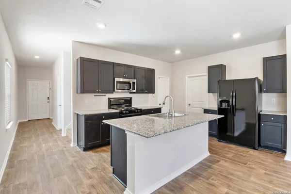 a large kitchen with stainless steel appliances granite countertop a stove a sink dishwasher a refrigerator and a oven with wooden floor