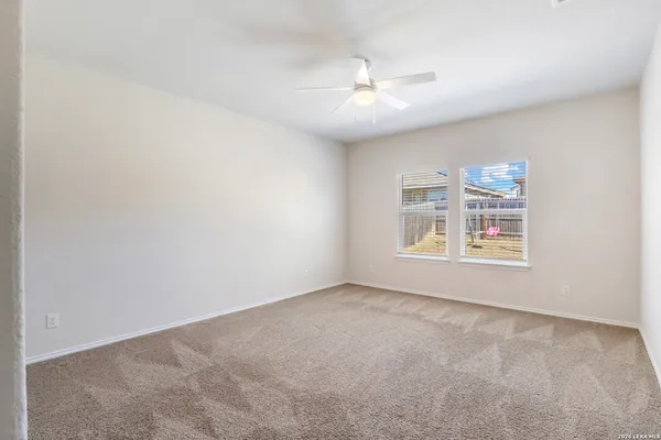 a view of an empty room with chandelier fan and fire place