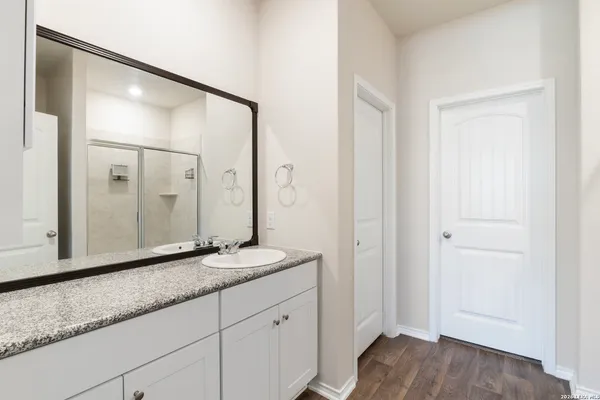 a bathroom with a granite countertop sink a mirror and a shower