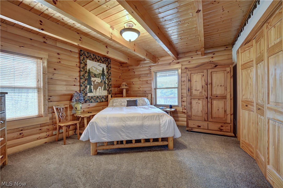 8045 McFadden Road Shreve, OH 44676 - Photo 31 of 45 Bedroom with a wooden ceiling with exposed beams, carpet, and log walls