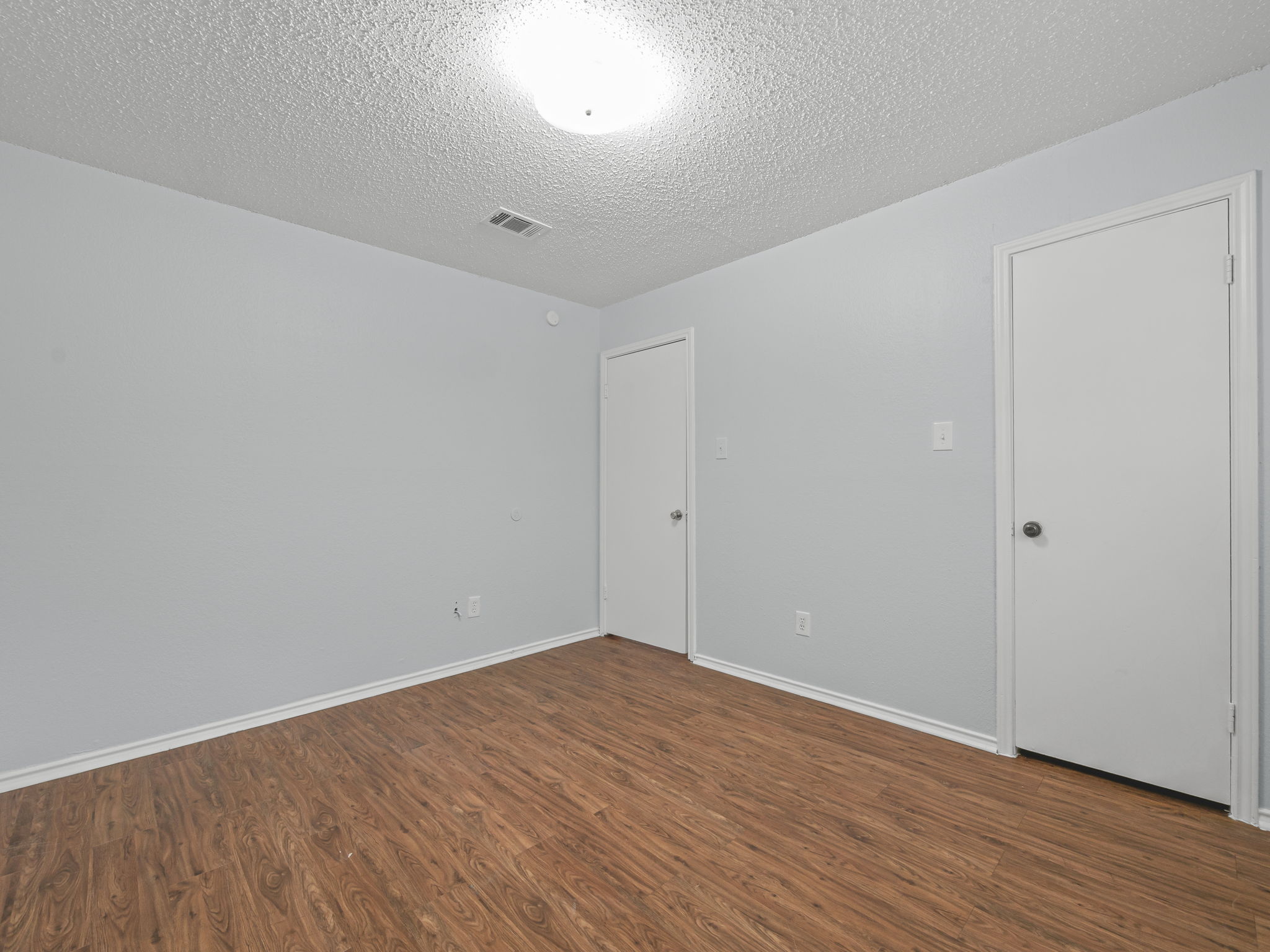 1816 Rawhide Loop, Unit 1822 Round Rock, TX 78681 - Photo 14 of 17 Empty room with wood finished floors and a textured ceiling