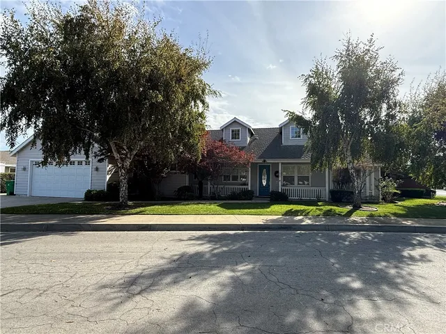 a front view of a house with a yard and large trees