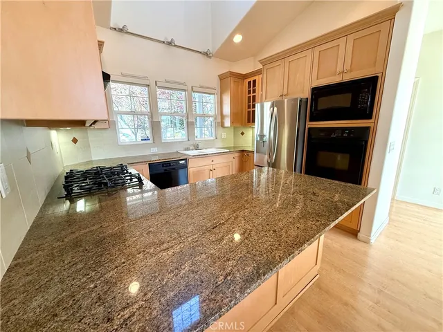 a kitchen with granite countertop a sink dishwasher stove and cabinets