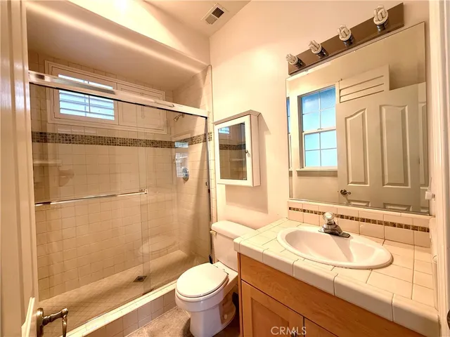 a bathroom with a granite countertop toilet a sink and a large mirror