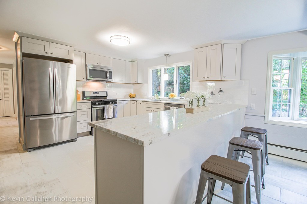 14 Pine Hill Road Framingham, MA 01701 - Photo 9 of 26 a kitchen with stainless steel appliances granite countertop a refrigerator a stove a sink a dining table and chairs with wooden floor