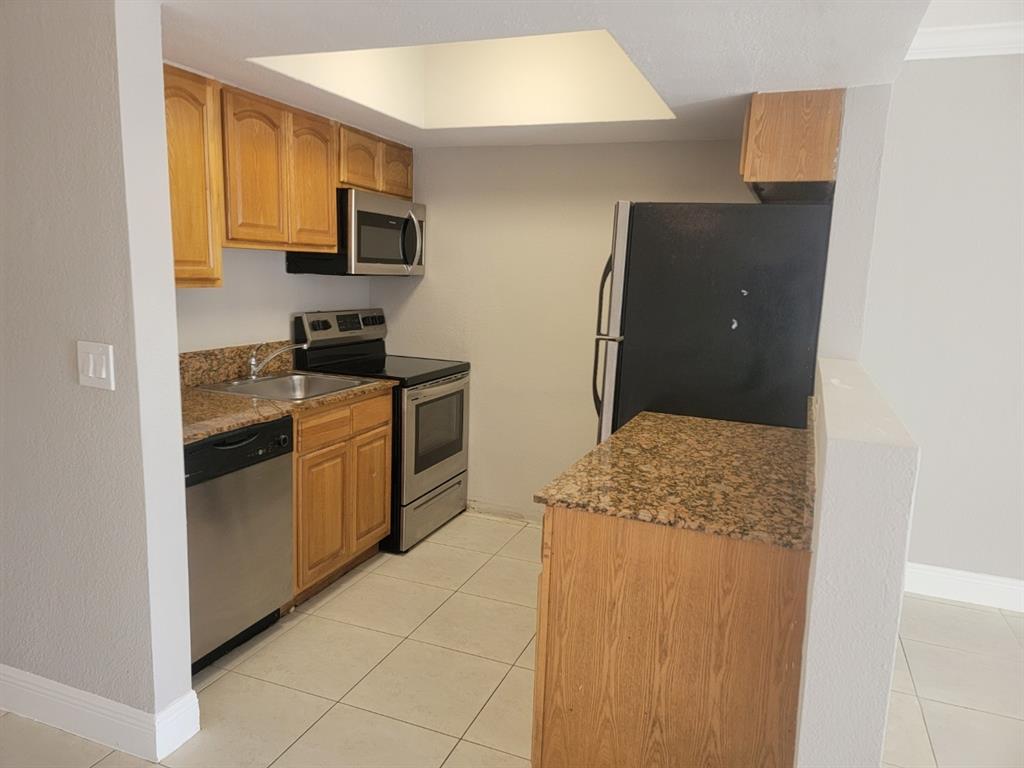 2100 Diana Drive, Unit 107 Hallandale Beach, FL 33009 - Photo 4 of 9 a kitchen with stainless steel appliances granite countertop a stove a sink and a refrigerator