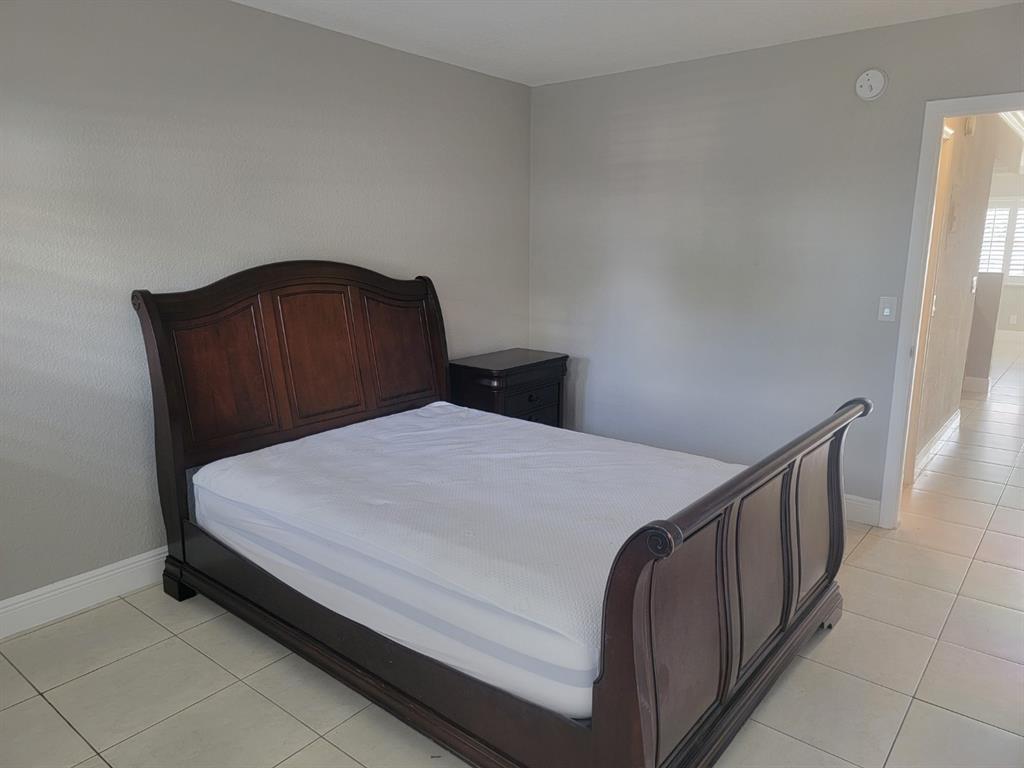 2100 Diana Drive, Unit 107 Hallandale Beach, FL 33009 - Photo 7 of 9 a bed sitting in a bedroom and wooden floor