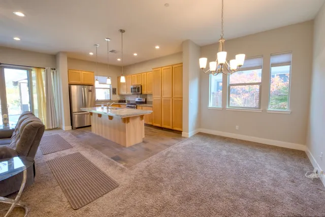 a kitchen with stainless steel appliances granite countertop a refrigerator oven a sink dishwasher and a dining table with chairs