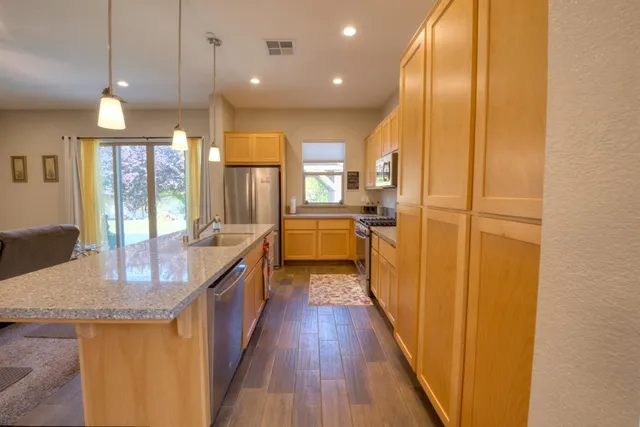 a kitchen with stainless steel appliances granite countertop counter space wooden floor and a window