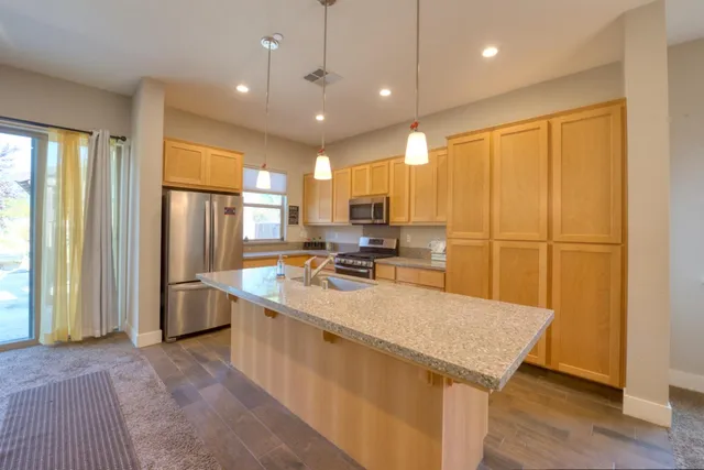 a large kitchen with kitchen island a large counter top space a sink stainless steel appliances and cabinets