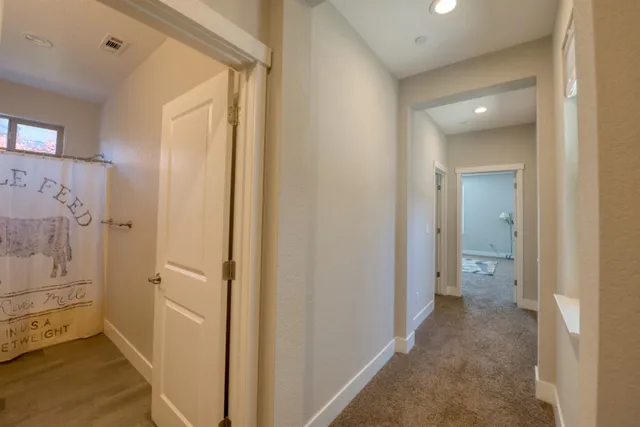 a view of a hallway with wooden floor and a bathroom