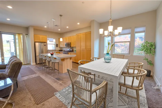 a kitchen with stainless steel appliances kitchen island granite countertop a stove a sink a dining table and chairs with wooden floor