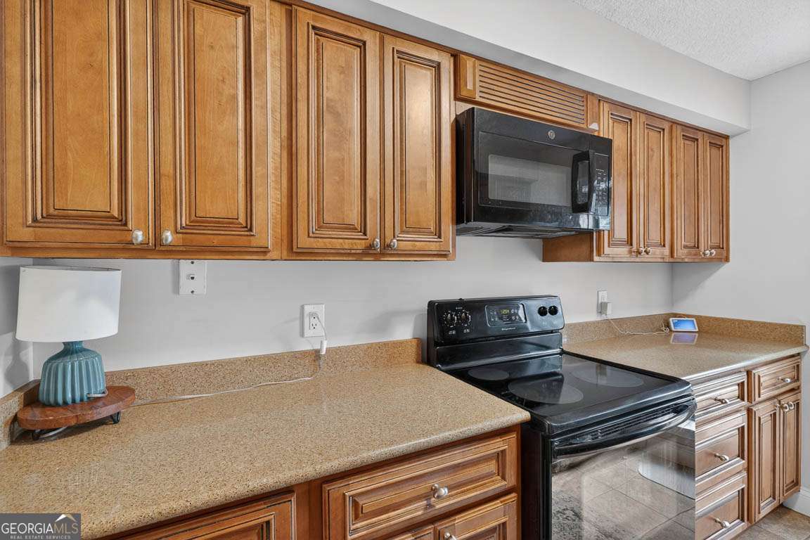 2514 Demere Road, Unit 7 St. Simons, GA 31522 - Photo 15 of 22 a kitchen with granite countertop a stove a sink and a microwave