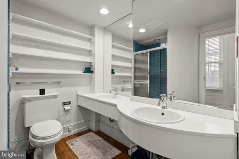 a view of a hallway with wooden floor and a bathroom