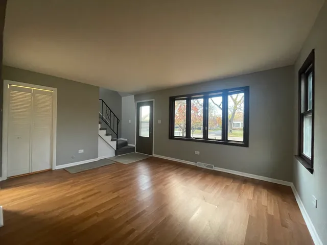 a view of an empty room with wooden floor fireplace and a window