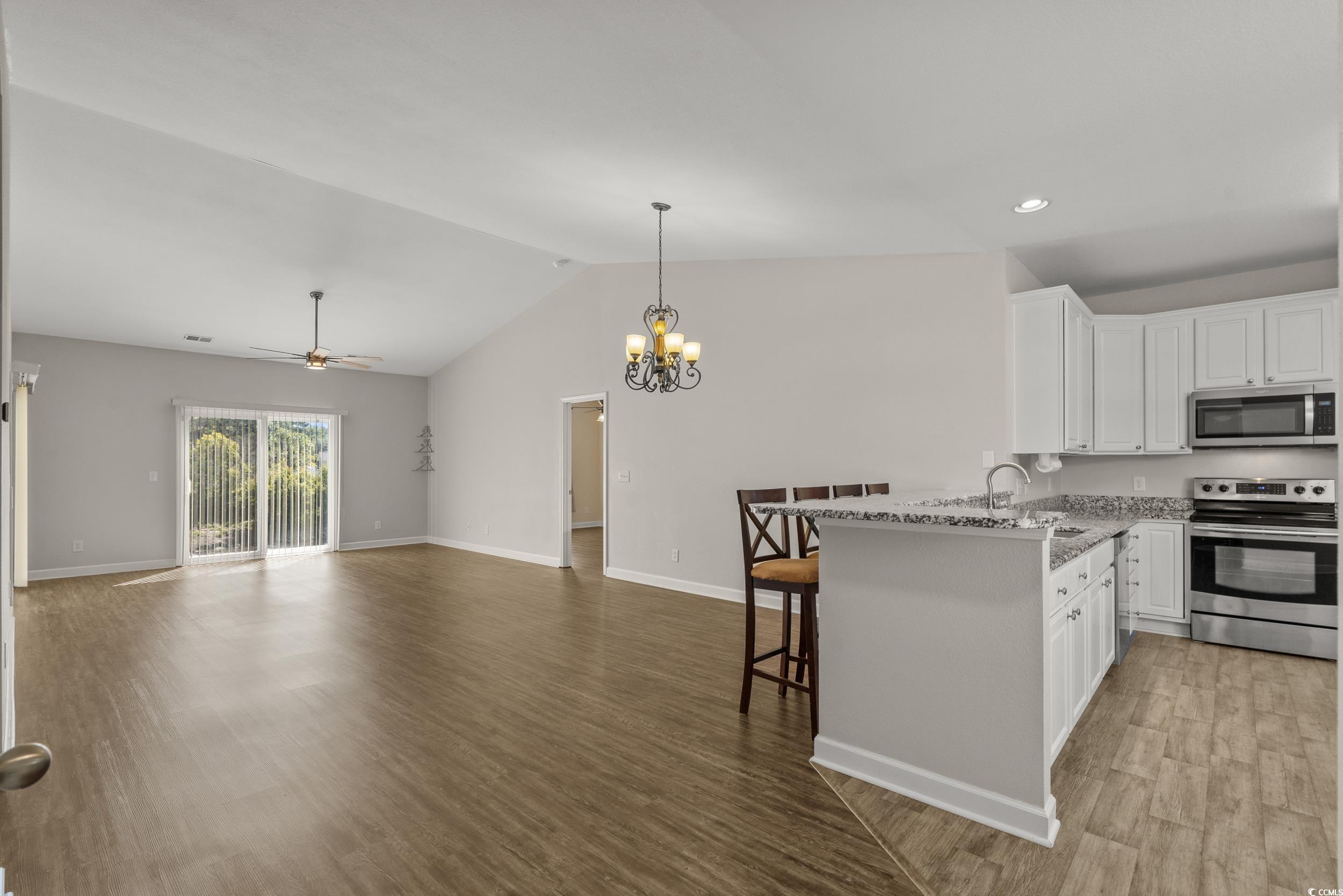 562 Tuckahoe Road Myrtle Beach, SC 29579 - Photo 11 of 40 Kitchen featuring white cabinetry, a kitchen bar, stainless steel appliances, a chandelier, and lofted ceiling