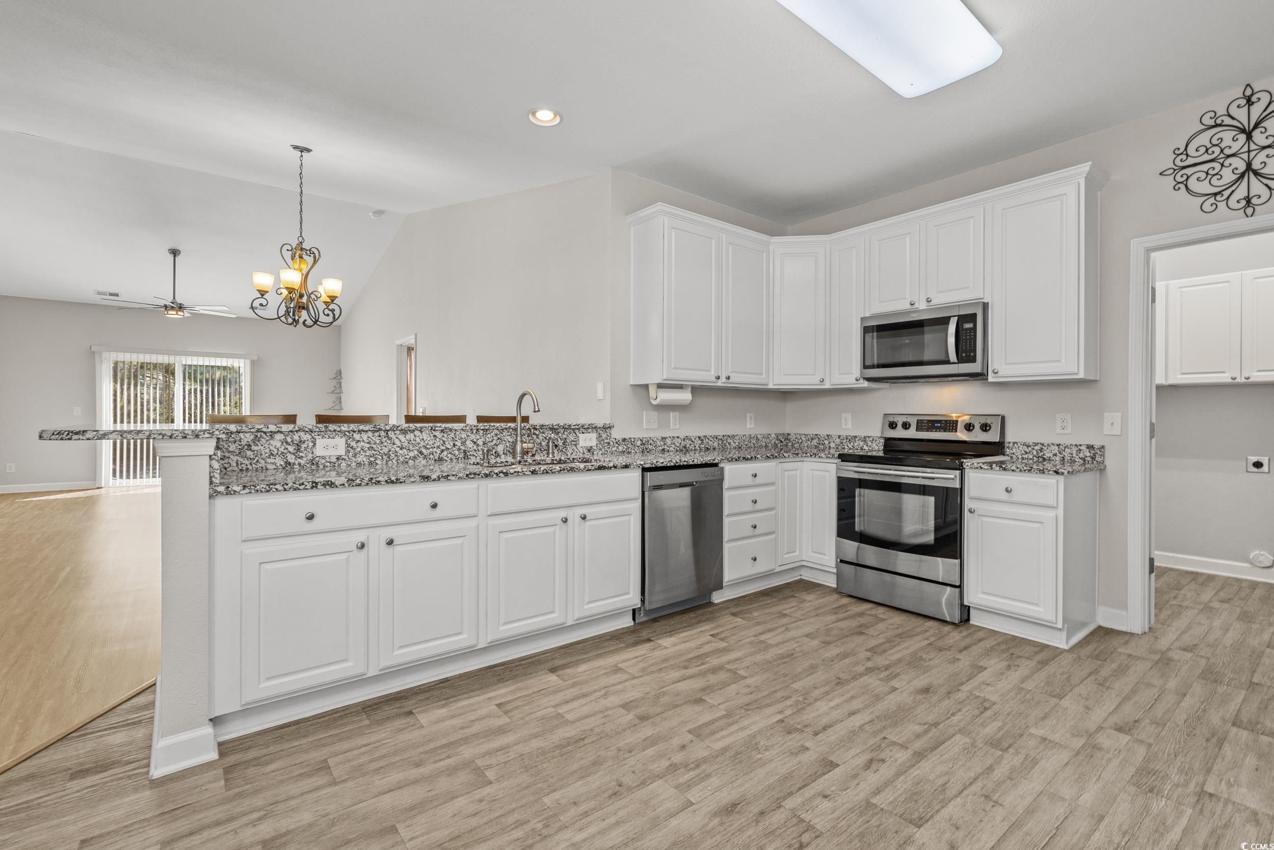 562 Tuckahoe Road Myrtle Beach, SC 29579 - Photo 5 of 40 Kitchen featuring appliances with stainless steel finishes, hanging light fixtures, white cabinets, vaulted ceiling, and light wood finished floors