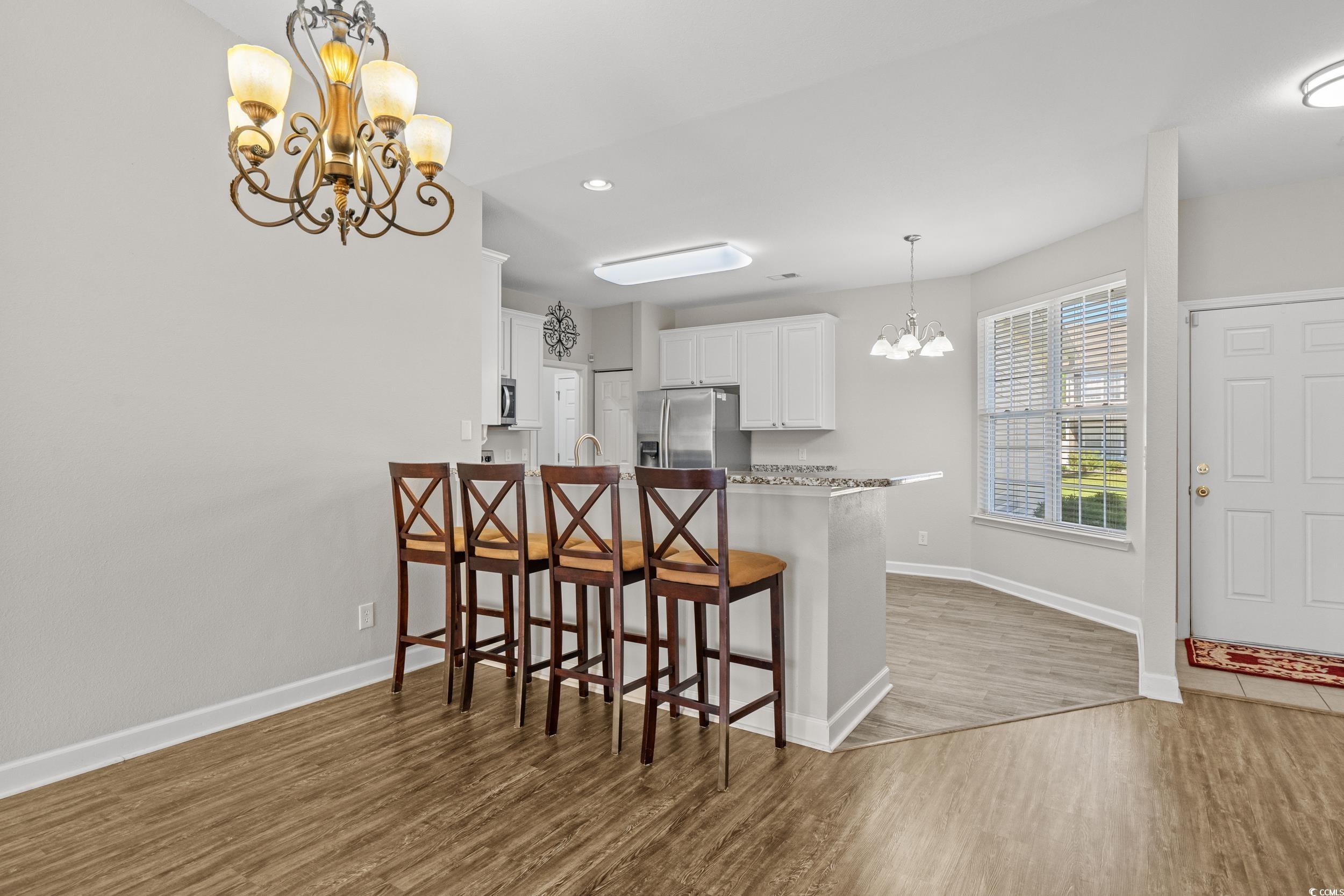 562 Tuckahoe Road Myrtle Beach, SC 29579 - Photo 6 of 40 Kitchen with a chandelier, a peninsula, a breakfast bar area, white cabinets, and dark wood-style floors