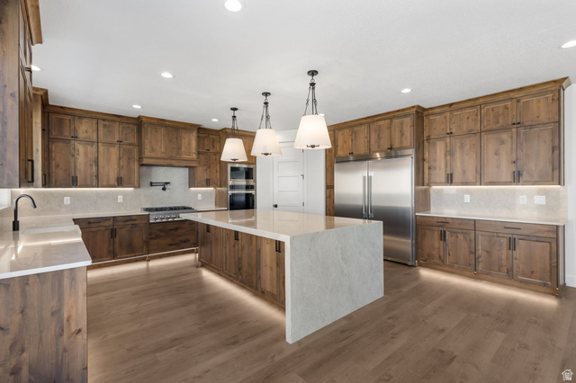 692 East Mountain Road North Ogden, UT 84414 - Photo 3 of 17 Gourmet kitchen featuring a large central island with pendant lighting, wood-finish cabinetry, stainless steel appliances, and wood-finish flooring