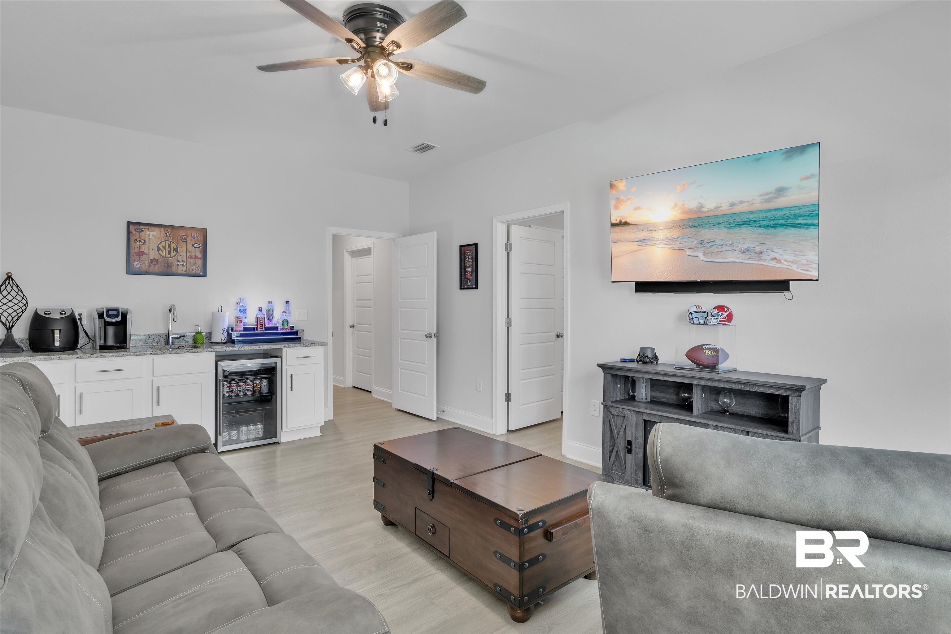 27862 Jade Court Daphne, AL 36526 - Photo 22 of 33 Living room with beverage cooler, light wood-style floors, ceiling fan, indoor wet bar, and baseboards