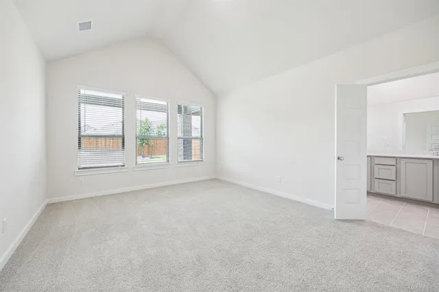 an empty room with windows and refrigerator