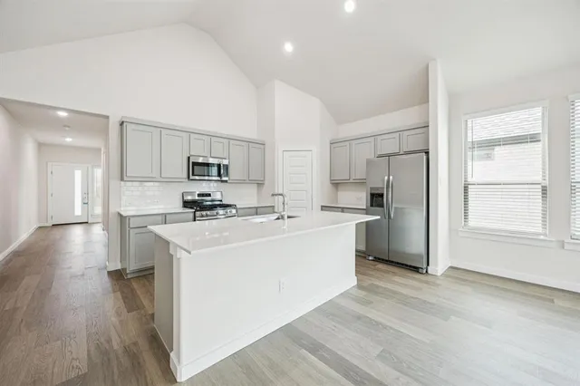 a kitchen with stainless steel appliances a refrigerator stove a sink and a oven with wooden floor