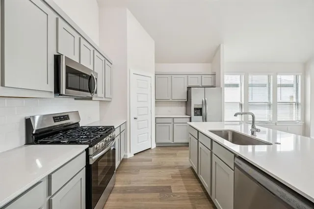 a kitchen with stainless steel appliances granite countertop a sink stove microwave and refrigerator